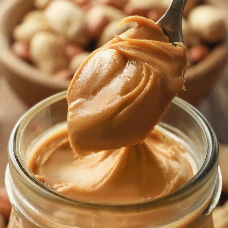 A spoon scooping peanut butter from a jar.