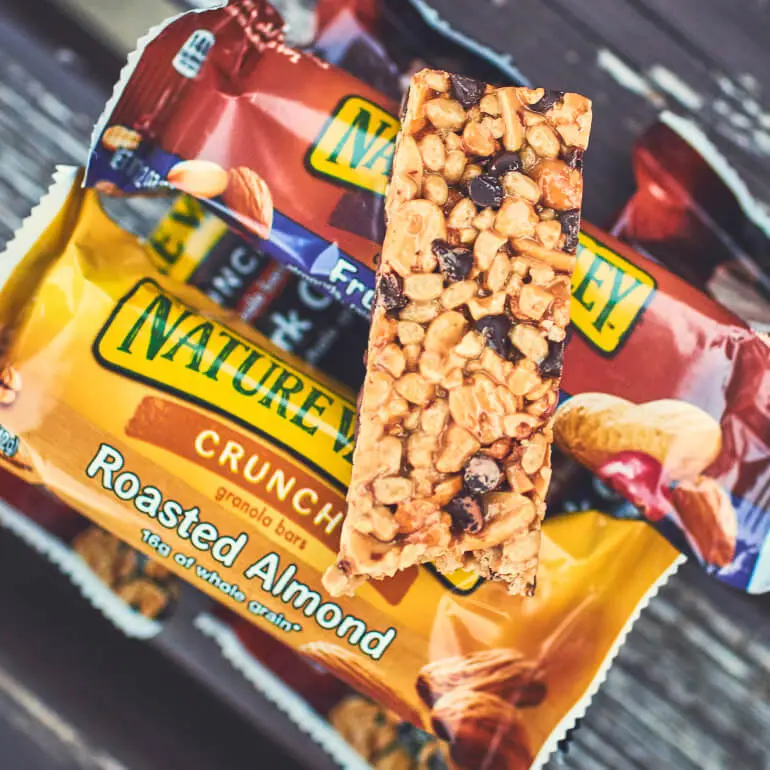 Unwrapped Nature Valley Oats and Dark Chocolate Bar placed over packaged Nature Valley Roasted Almond and Nature Valley Fruit Nut bars.