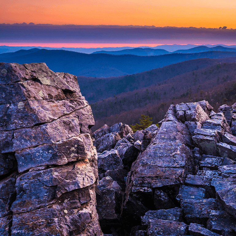 Split rock formations in the foreground and sunset colors in the background at Shenandoah National Park.