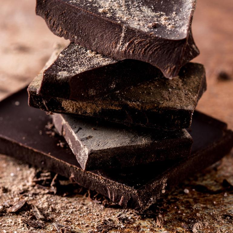 Five slabs of dark chocolate stacked on table.