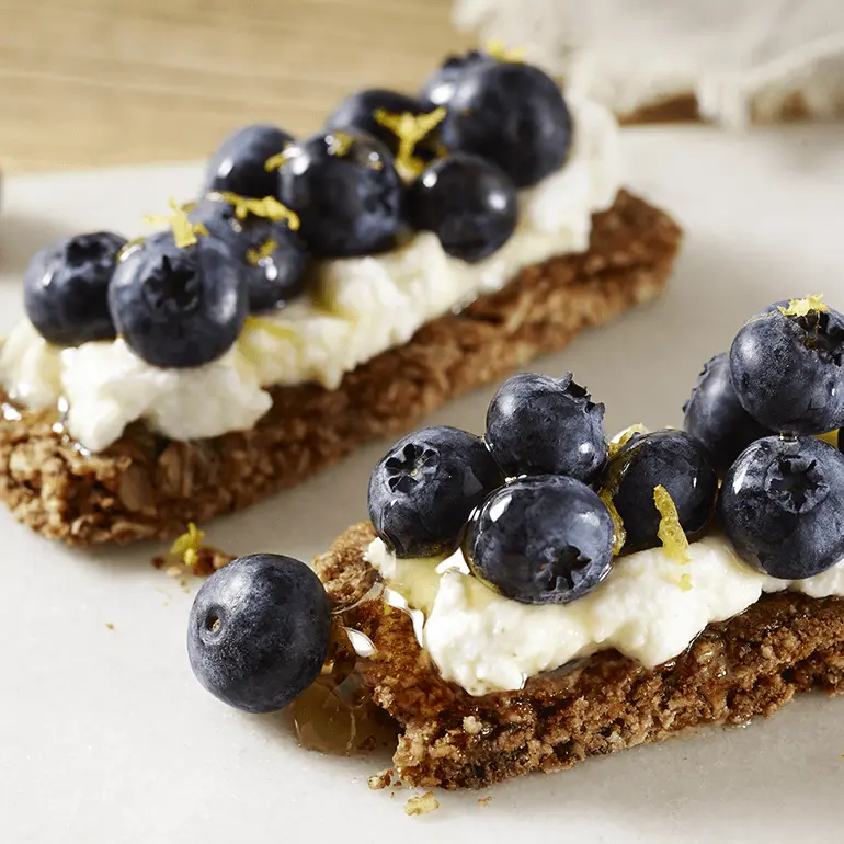 Two Nature Valley Oats 'N Honey Crunchy Granola Bars topped with ricotta, honey, and blueberries.