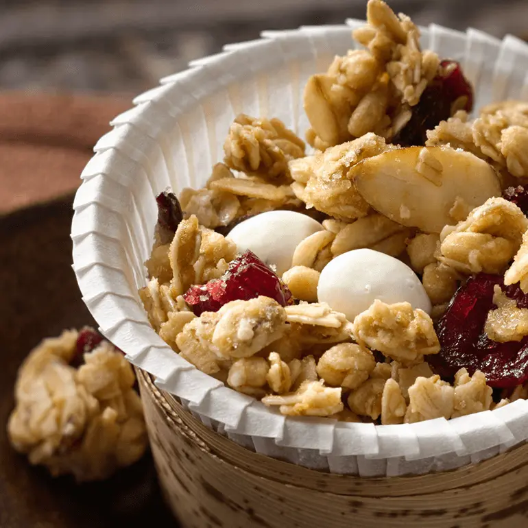 Snack mix made with Nature Valley Cranberry Almond Protein Granola, dried cranberries, and yogurt-covered raisins, served in a paper cup.
