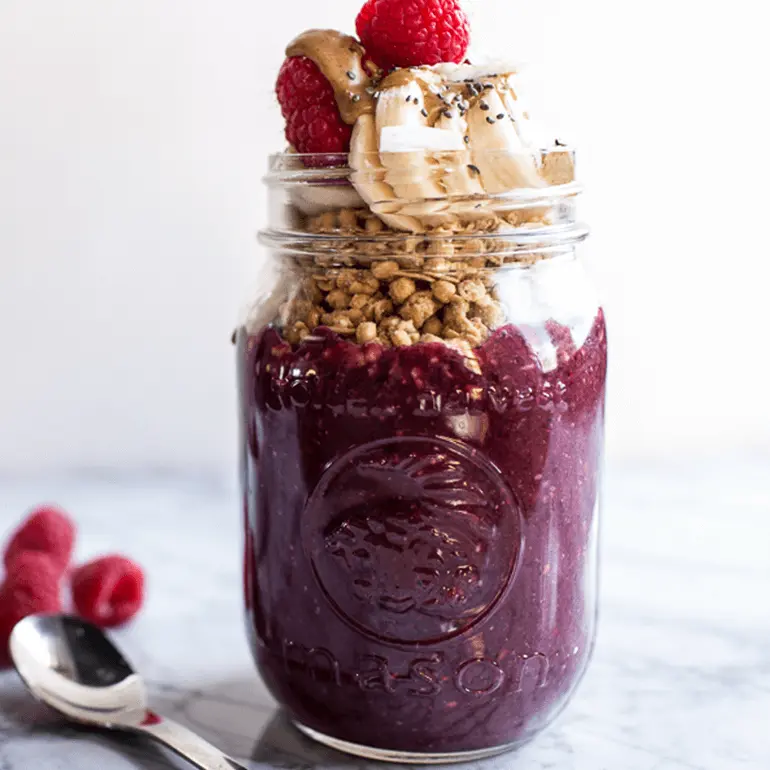 Acai, fruit, and chia seed smoothie with Nature Valley Coconut & Almond Granola and banana in a mason jar.