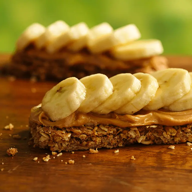 Nature Valley Oats 'N Honey Crunchy Granola Bars topped with sliced bananas and peanut butter.