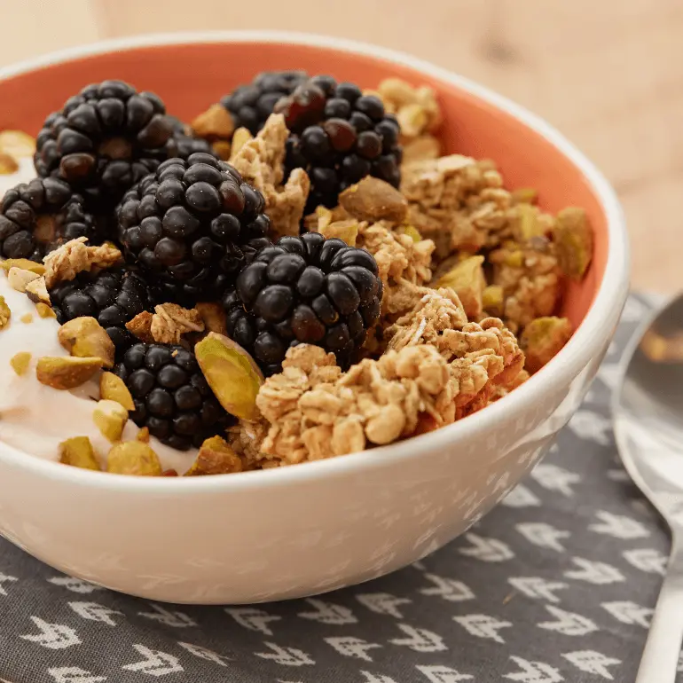 Peach Yogurt bowl topped with with Nature Valley Oats 'N Honey Protein Granola, blackberries, and pistachios.