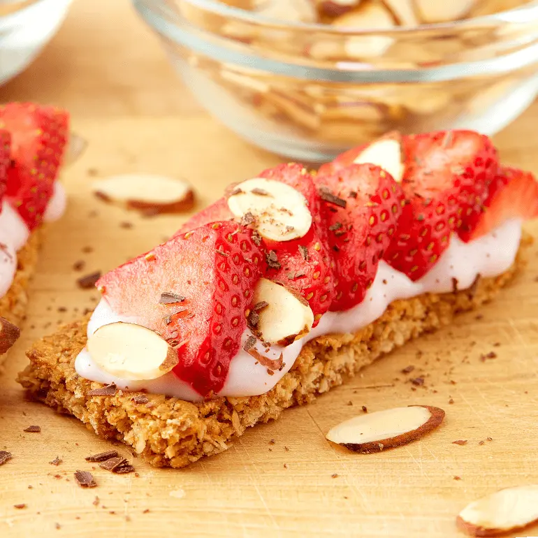Nature Valley Oats 'N Honey Crunchy Granola Bar spread with yogurt topped with strawberries, shaved chocolate and sliced almonds.
