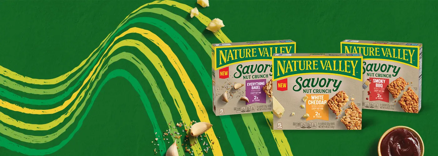 A family shot of three Nature Valley Savory Nut Crunch Bars, Everything Bagel, White Cheddar, and Savory BBQ on a green background with a yellow and green line pattern and a cup of BBQ sauce and garlic cloves.