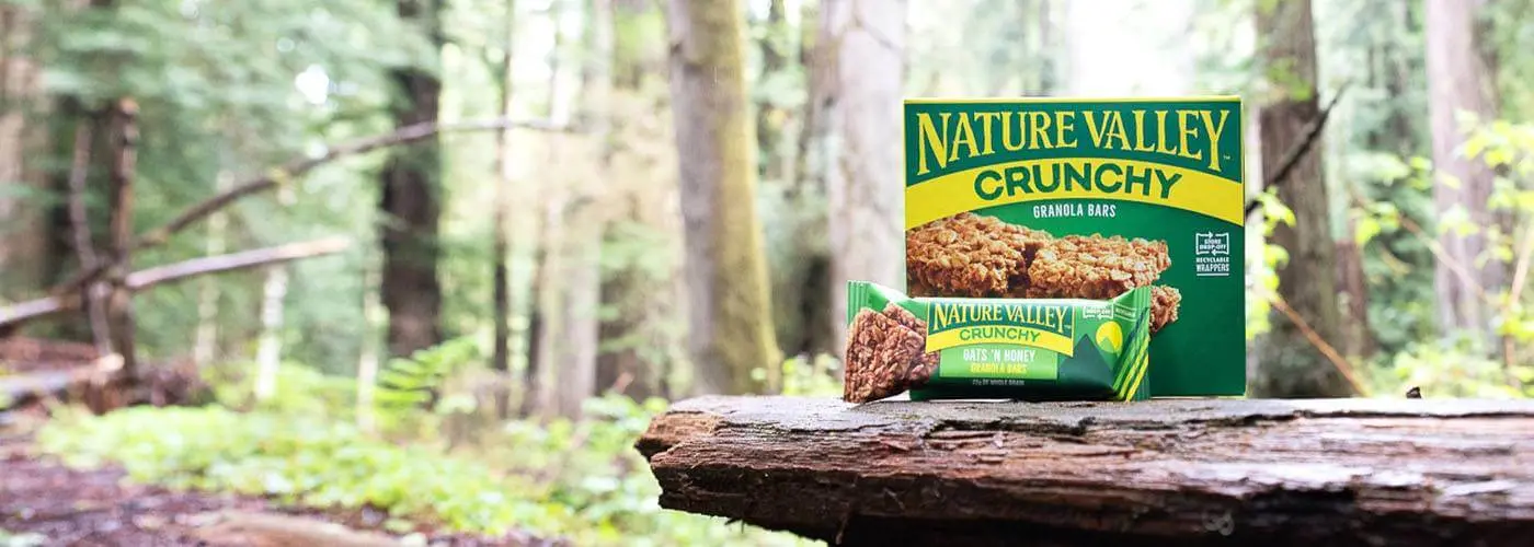 Nature Valley Crunchy Granola Bars, front of box and a single pack, sitting on a tree stump.