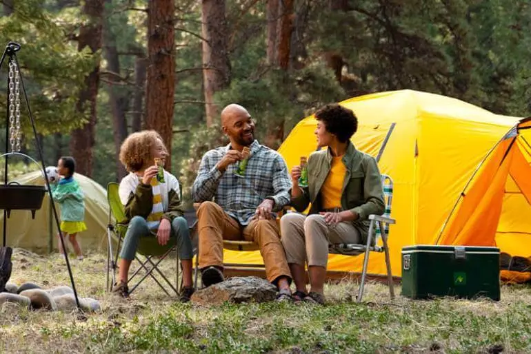 A family sitting in chairs near a tent, enjoying the outdoors together.