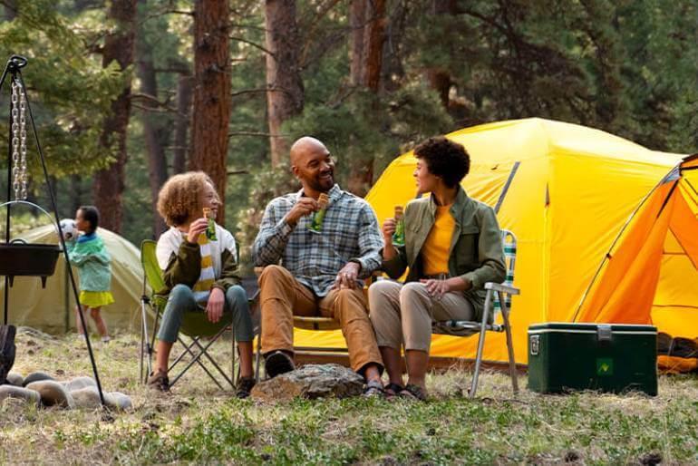 A family sitting in chairs near a tent, enjoying the outdoors together.