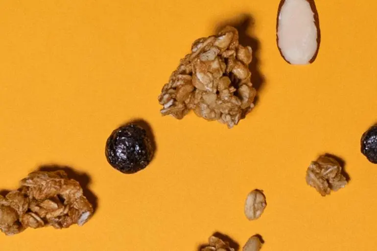 A orange background with scattered granola and raisins